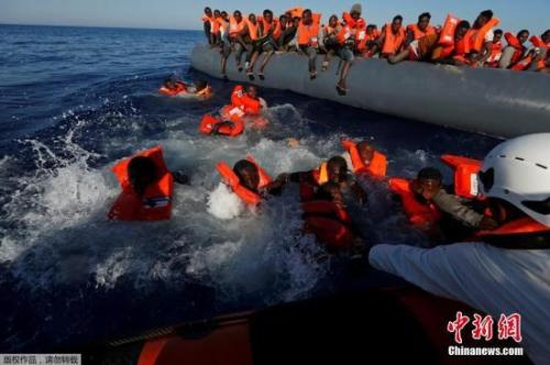 资料图：当地时间2017年4月14日，利比亚Zawiya附近海域，移民从乘坐的橡皮艇落水后浮在水面上。 